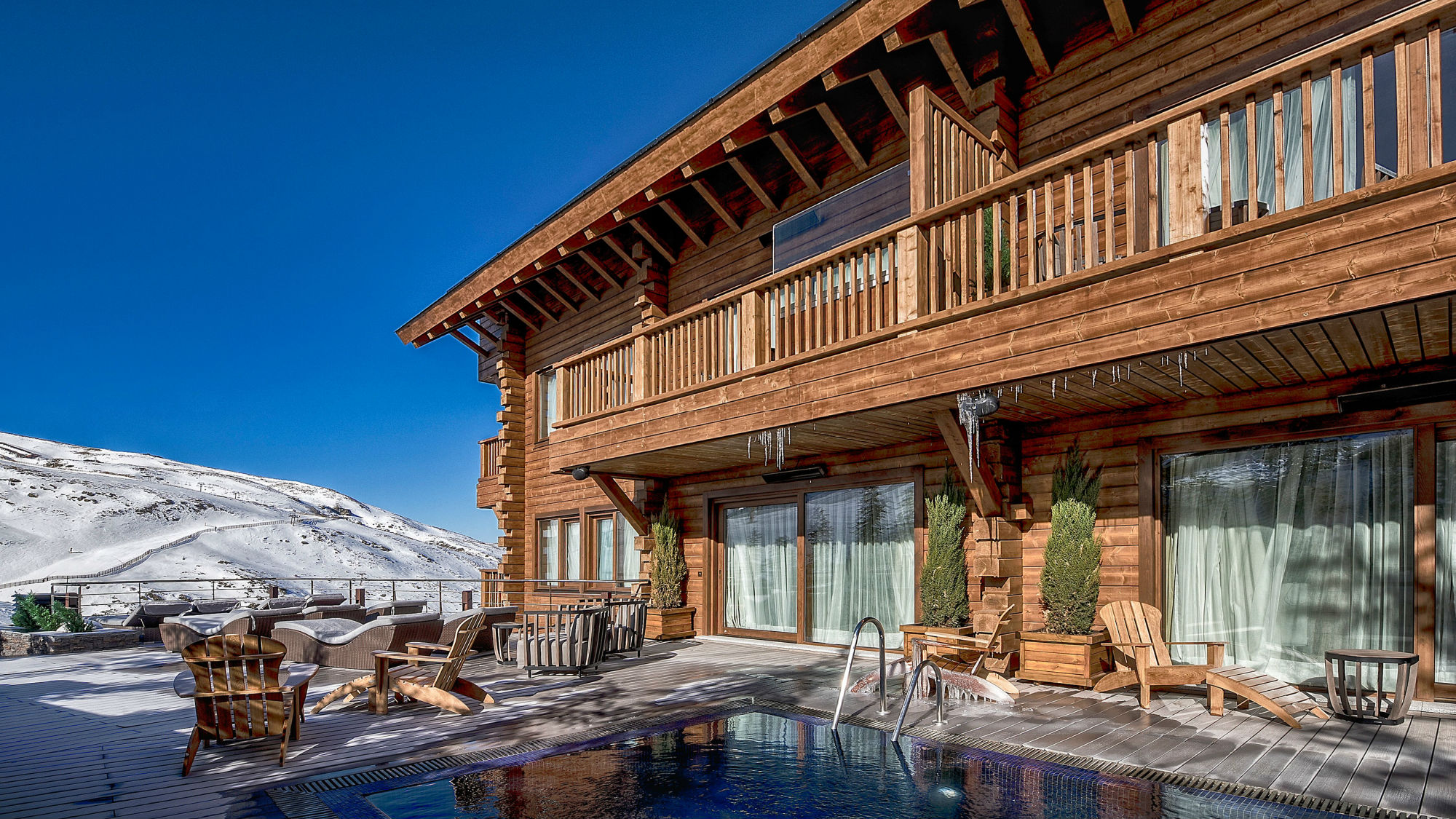 Luxury wooden chalet with private pool and terrace overlooking the snow-covered Sierra Nevada slopes